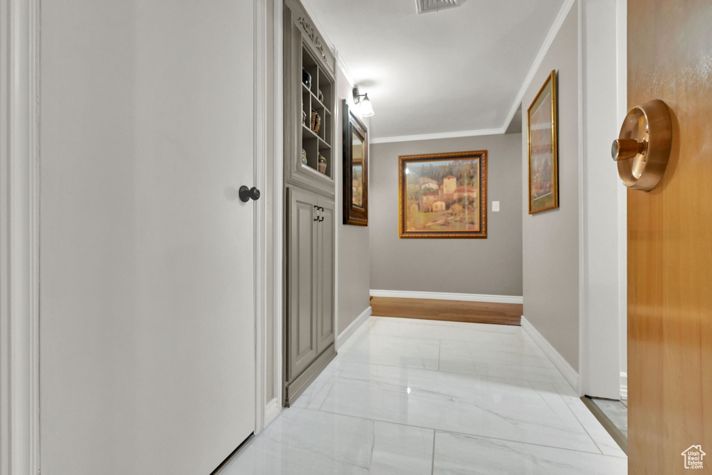 Corridor with light marble finish flooring and crown molding