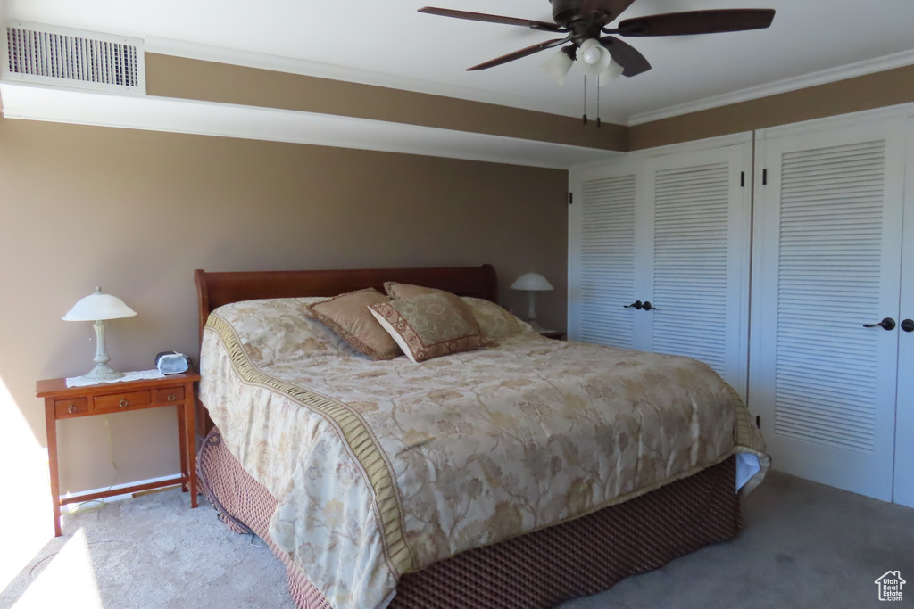 Bedroom with carpet floors, a closet, ornamental molding, and ceiling fan