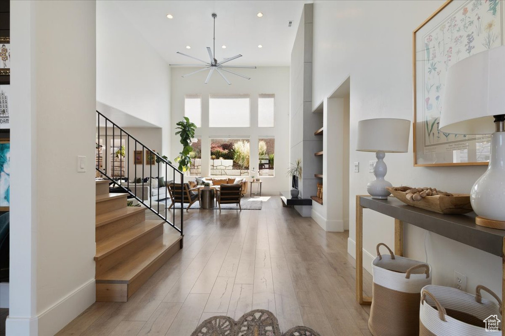 Foyer with a towering ceiling, light wood-style floors, stairs, and recessed lighting