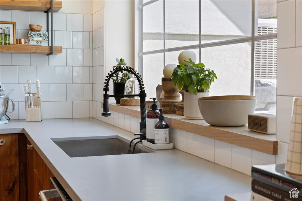 Kitchen featuring healthy amount of natural light, open shelves, decorative backsplash, and light countertops