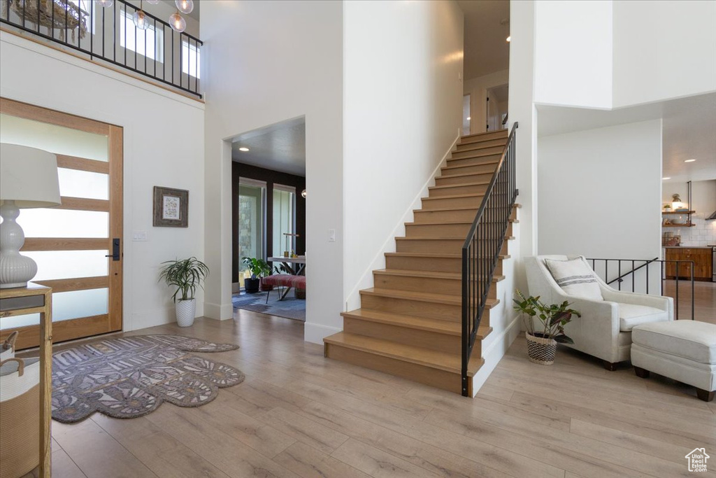 Foyer entrance with a towering ceiling, wood finished floors, stairway, and healthy amount of natural light