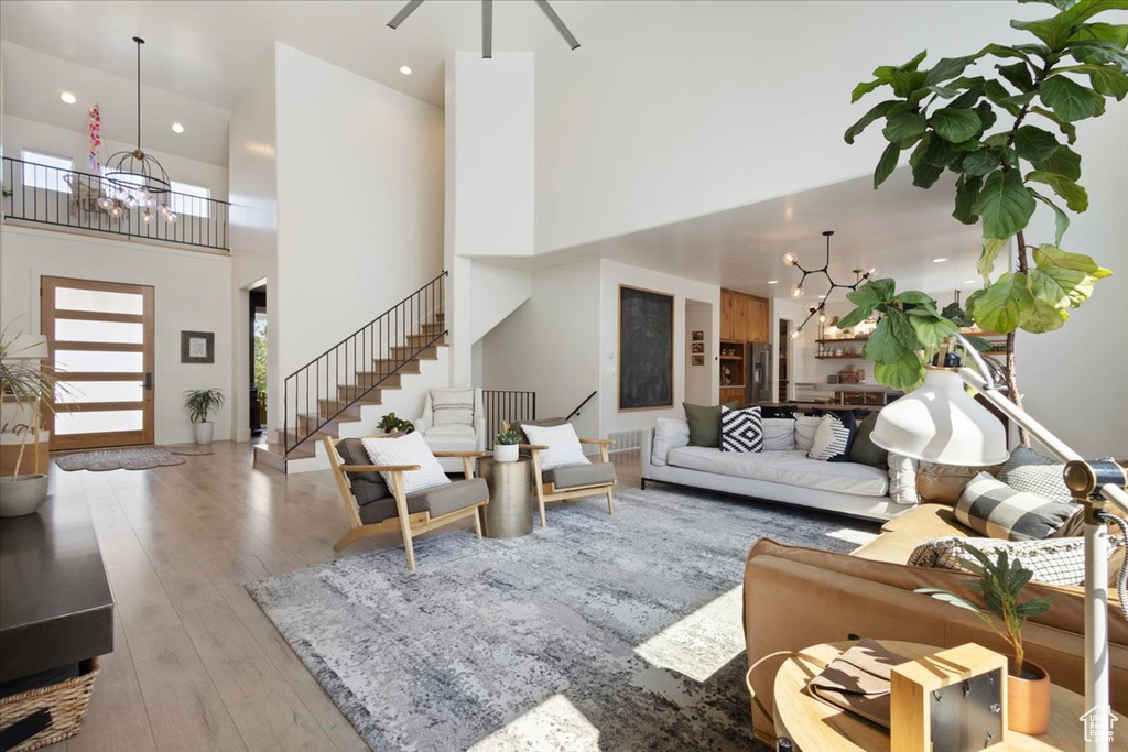 Living room with a chandelier, stairs, hardwood / wood-style flooring, a high ceiling, and recessed lighting