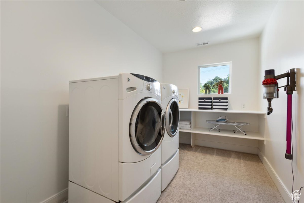 Laundry room with washing machine and dryer, light carpet, and recessed lighting