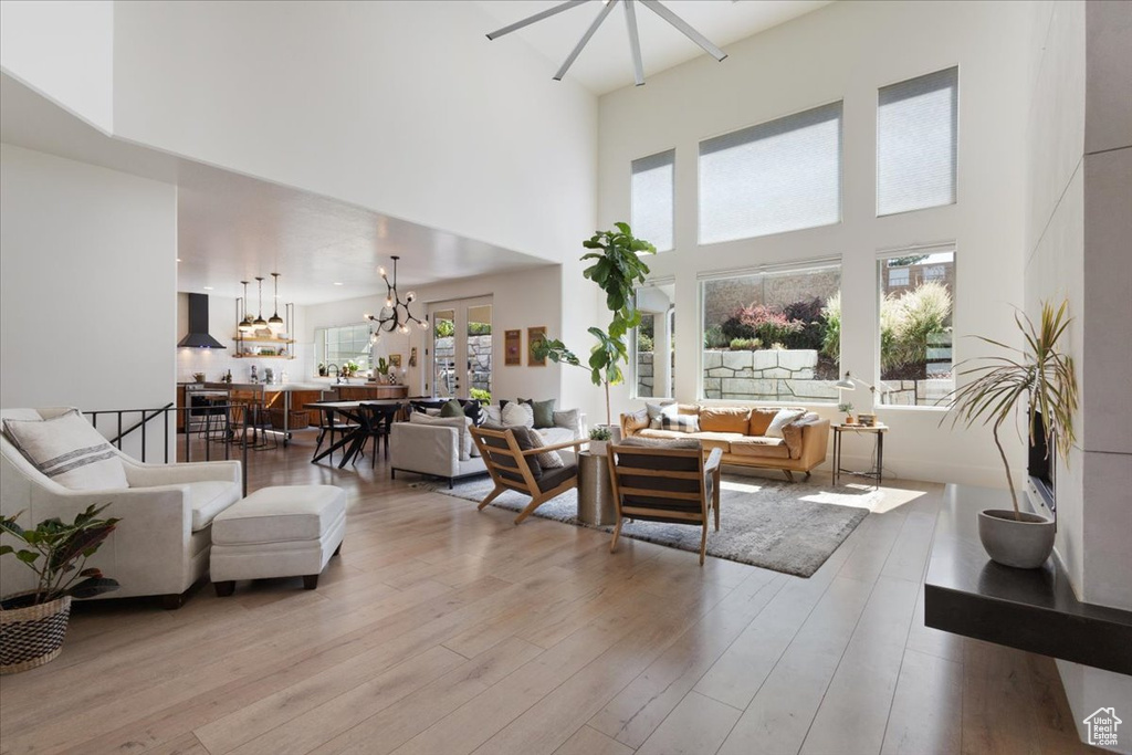 Living room featuring a chandelier, a towering ceiling, and wood finished floors
