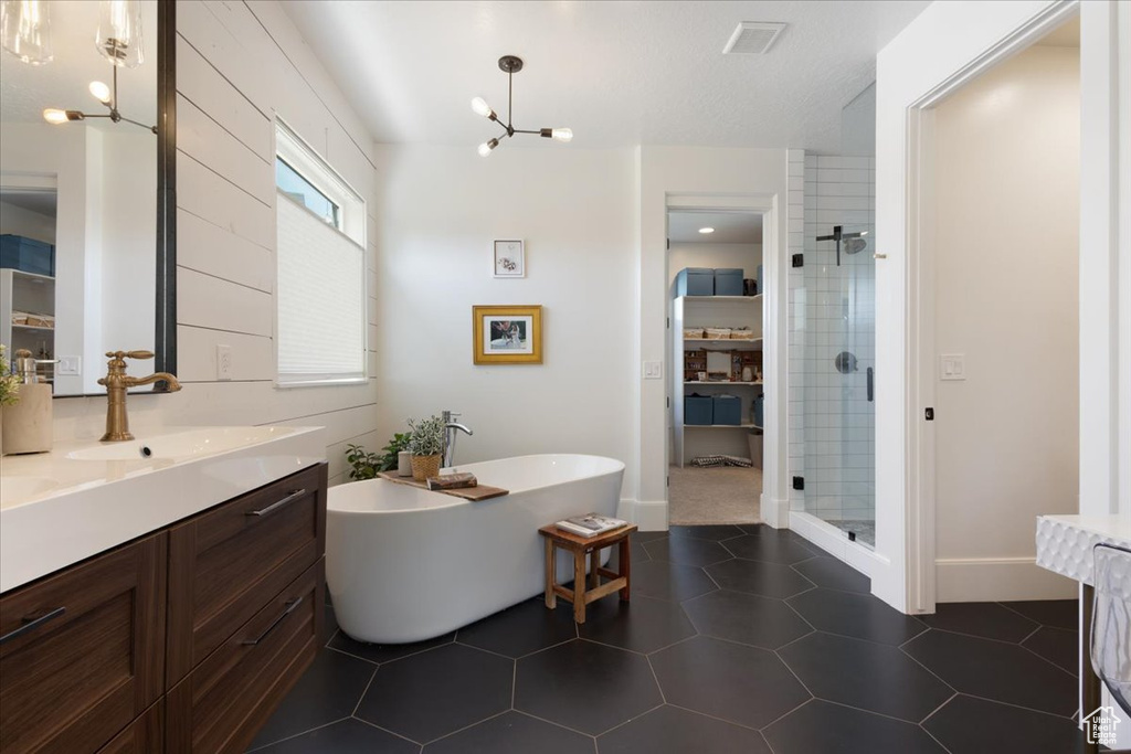 Bathroom featuring a stall shower, vanity, a freestanding tub, and a chandelier
