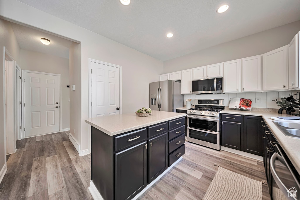 Kitchen with appliances with stainless steel finishes, dark cabinets, white cabinetry, light countertops, and recessed lighting