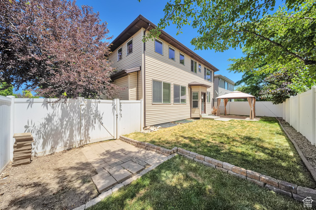 Back of property with a gazebo, a patio area, entry steps, and a fenced backyard