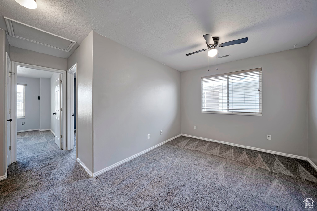 Carpeted spare room featuring a ceiling fan and a textured ceiling