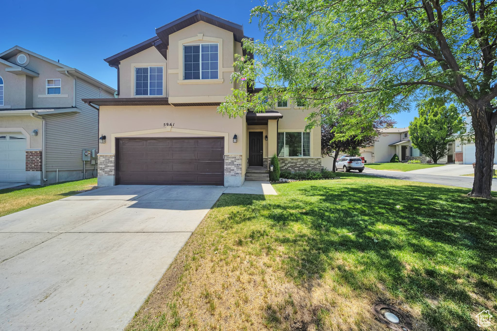 View of front of house featuring stucco siding, stone siding, a garage, a front lawn, and concrete driveway