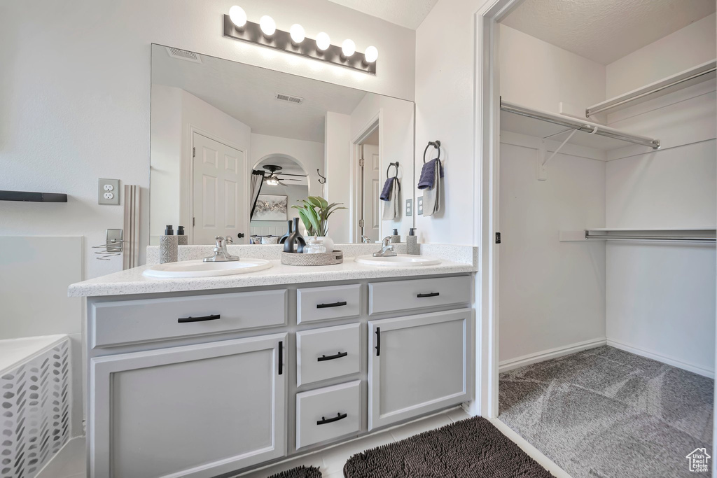 Full bath featuring double vanity, ceiling fan, and a spacious closet