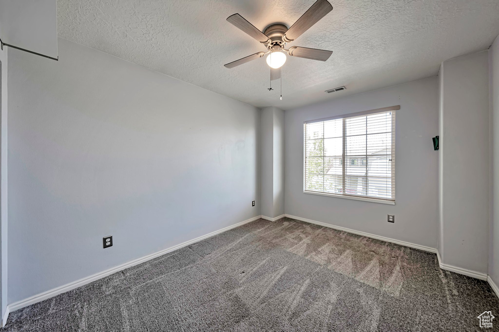 Unfurnished room featuring a textured ceiling, carpet floors, and ceiling fan