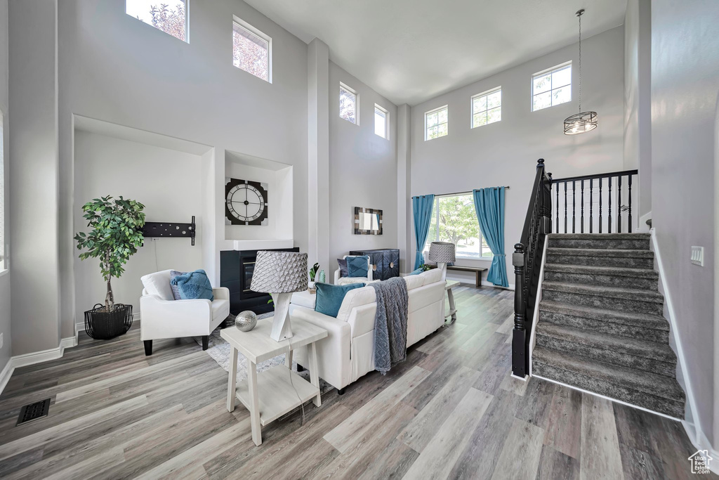 Living room featuring a high ceiling, plenty of natural light, wood finished floors, and stairs
