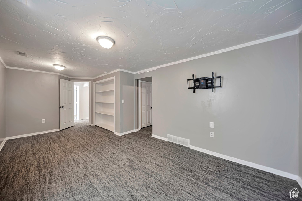 Carpeted empty room with built in features and ornamental molding
