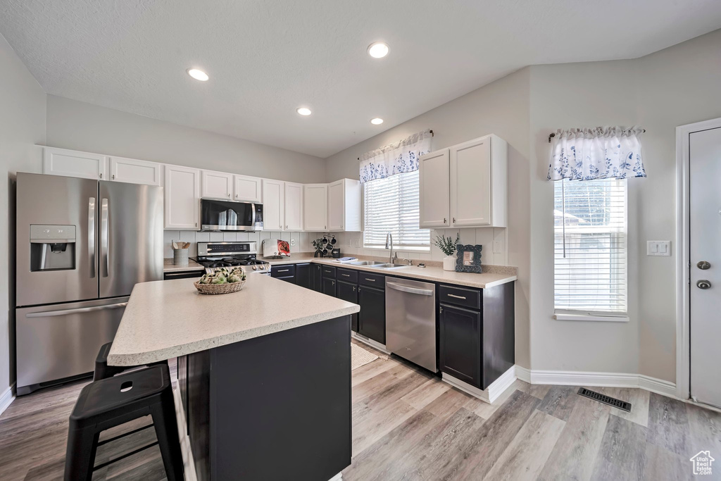 Kitchen featuring stainless steel appliances, white cabinets, light countertops, light wood finished floors, and recessed lighting