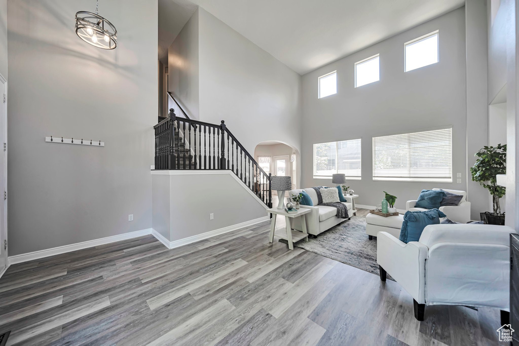 Living area with stairway, high vaulted ceiling, arched walkways, and wood finished floors