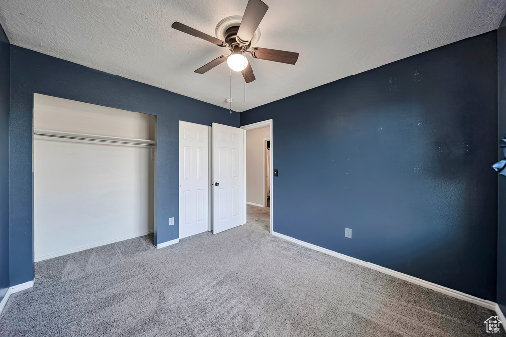Unfurnished bedroom featuring carpet flooring, a closet, a ceiling fan, and a textured ceiling