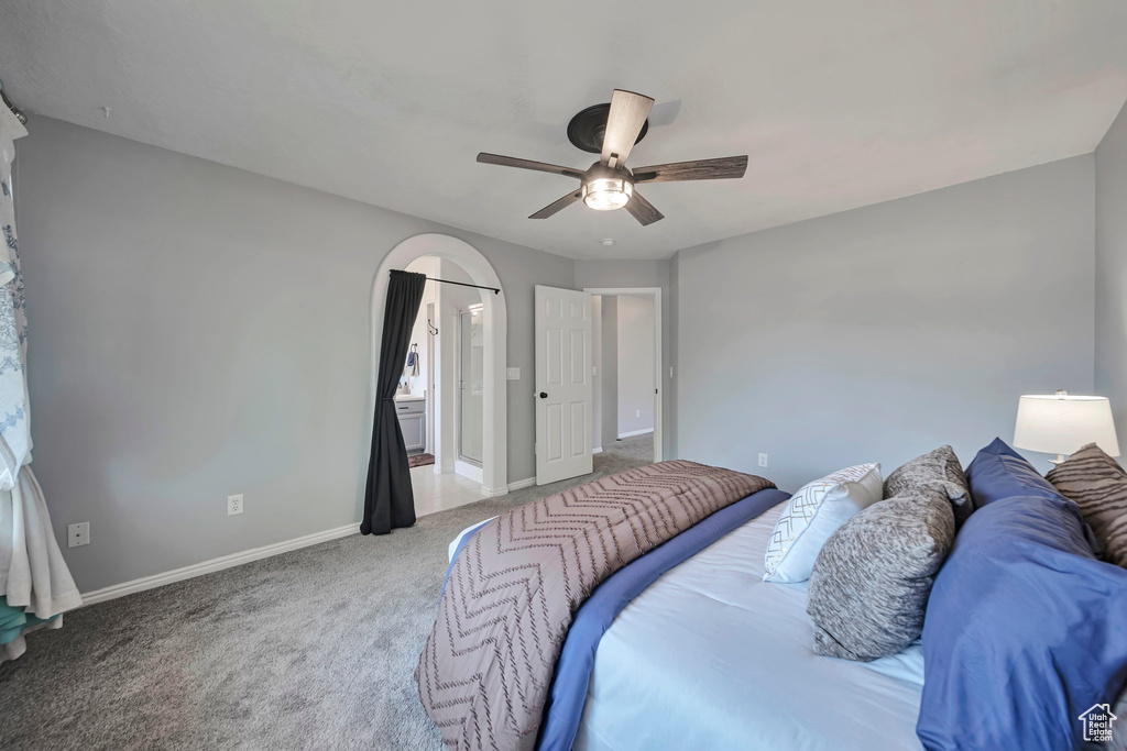 Carpeted bedroom with ceiling fan and connected bathroom