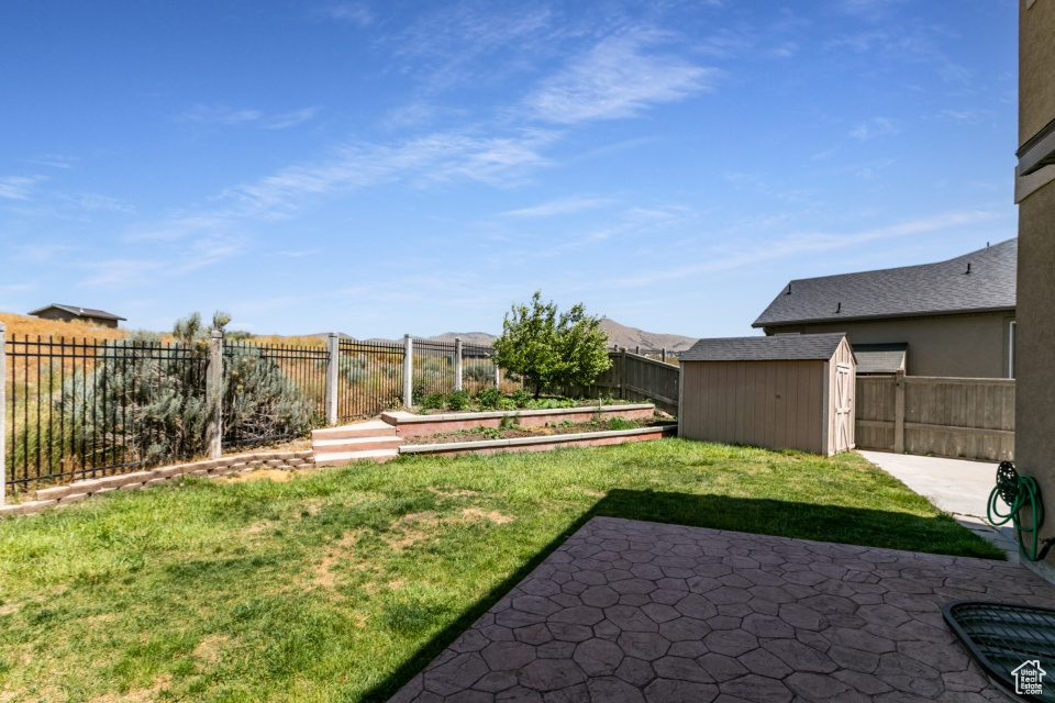 Fenced backyard with a patio, a shed, and a vegetable garden