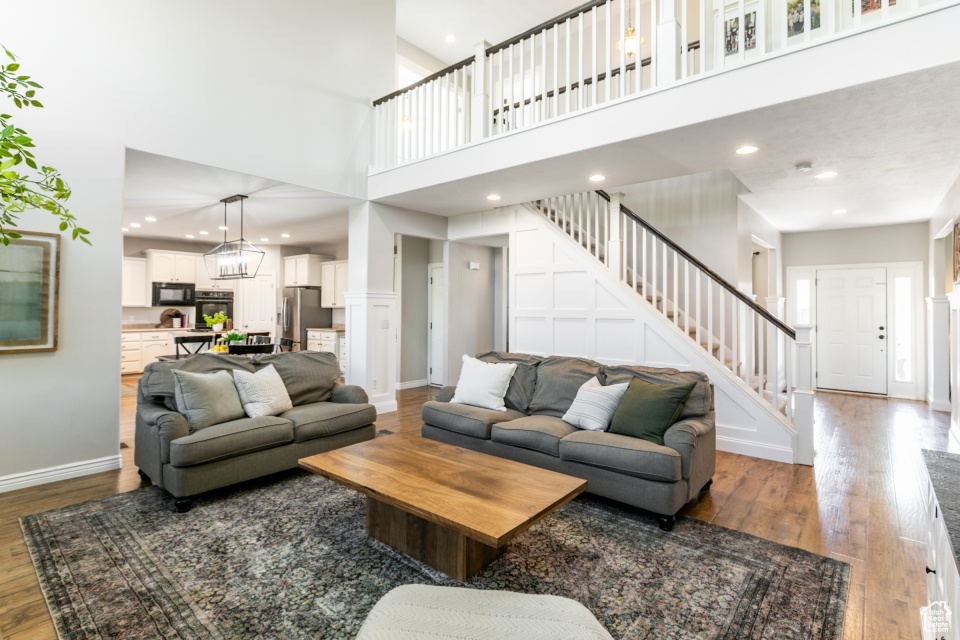 Living area featuring stairs, a high ceiling, wood finished floors, and recessed lighting