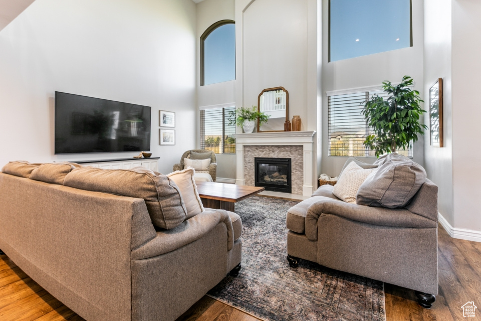 Living room with a high ceiling, wood finished floors, and a premium fireplace