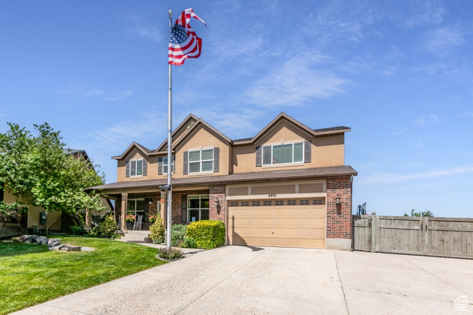 View of front of home featuring driveway, a garage, a porch, stucco siding, and brick siding