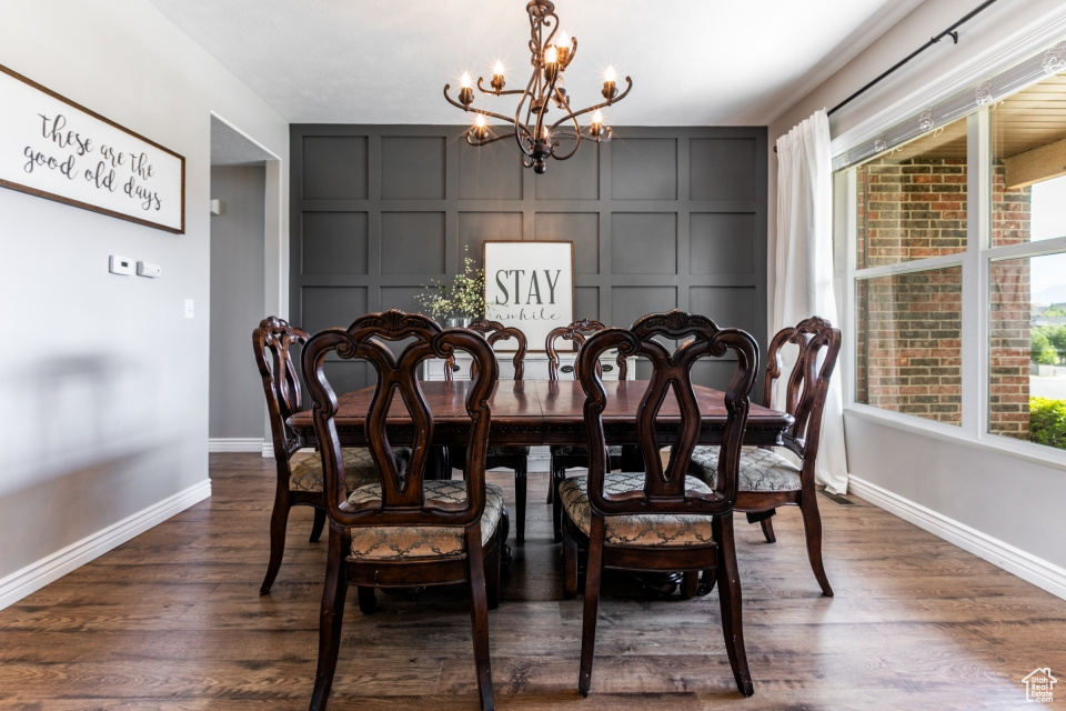 Dining room with a decorative wall, a chandelier, dark wood-style floors, and plenty of natural light