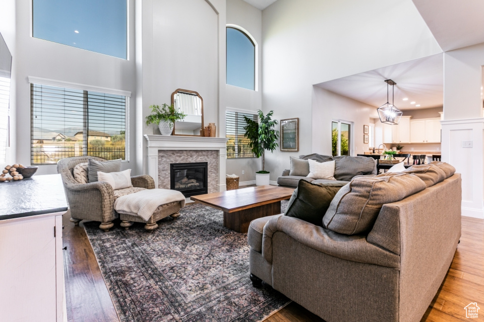 Living room with a high ceiling, a glass covered fireplace, and light wood-style flooring
