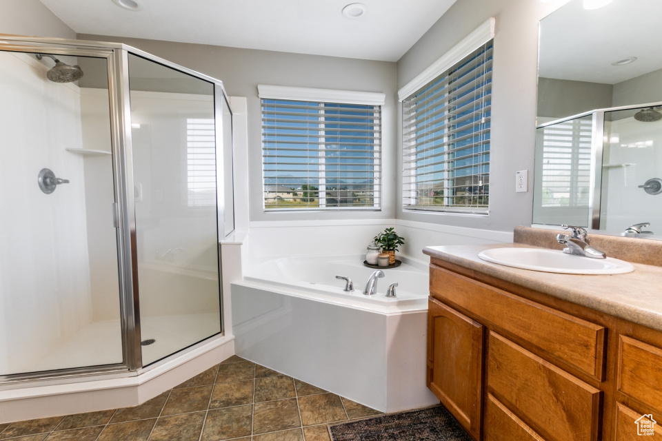 Bathroom featuring a stall shower, vanity, and a garden tub