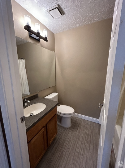 Bathroom with a textured ceiling, vanity, and wood finished floors