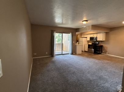 Unfurnished living room with a textured ceiling and dark colored carpet