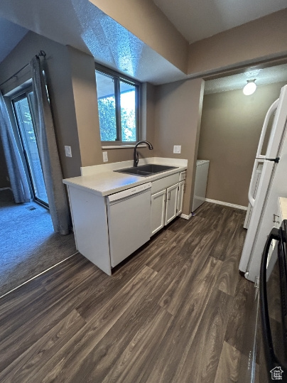 Kitchen featuring white appliances, dark wood finished floors, light countertops, white cabinets, and healthy amount of natural light