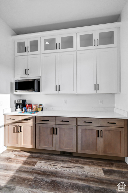 Bar area featuring stainless steel microwave and dark wood-style flooring