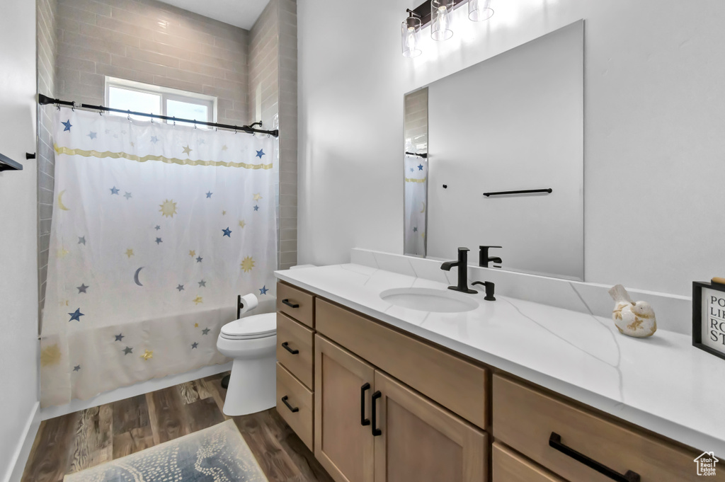 Full bath featuring vanity, wood finished floors, and shower / tub combo with curtain