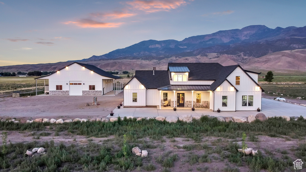 Modern farmhouse featuring a standing seam roof, a metal roof, a mountain view, a porch, and a garage