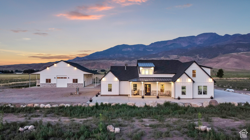 Back of property with a standing seam roof, a mountain view, a metal roof, a garage, and covered porch