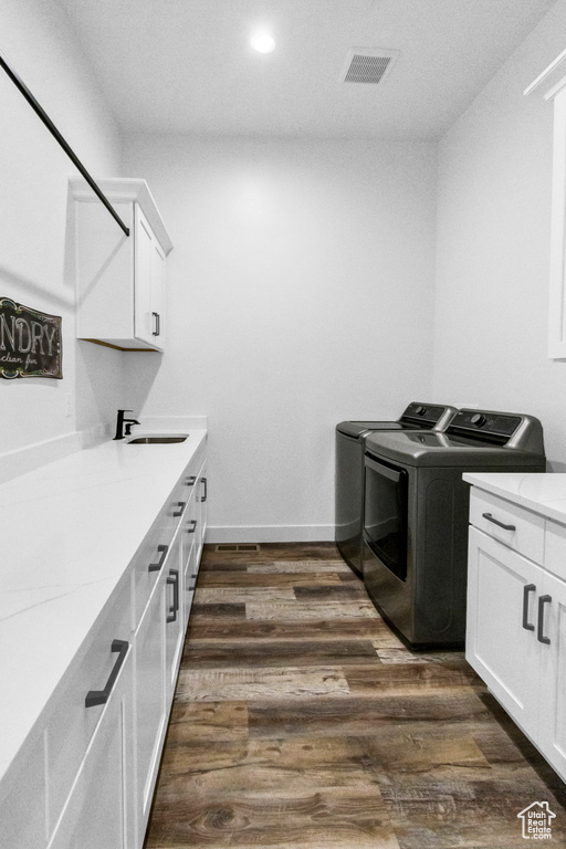 Washroom featuring washer and clothes dryer, cabinet space, dark wood finished floors, and recessed lighting