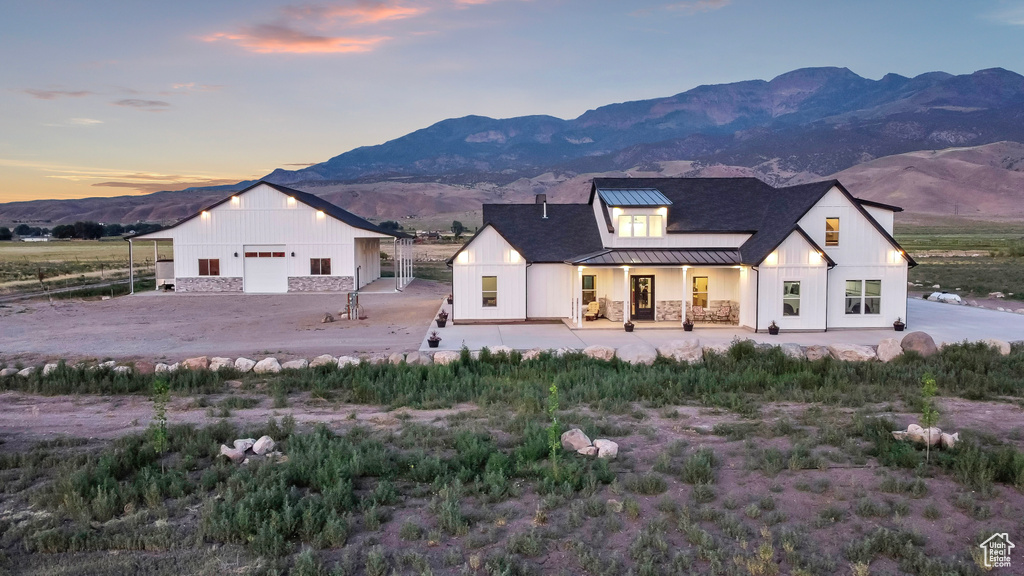 Modern farmhouse featuring a standing seam roof, a mountain view, a metal roof, and an outdoor structure