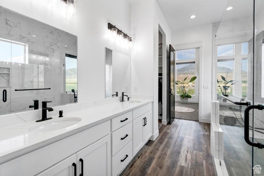 Bathroom with plenty of natural light, double vanity, recessed lighting, a marble finish shower, and wood finished floors