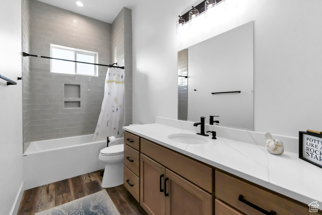 Bathroom featuring vanity, wood finished floors, and shower / tub combo with curtain