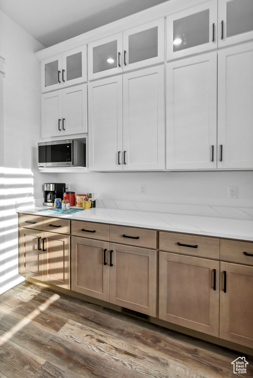 Bar featuring stainless steel microwave and dark wood finished floors