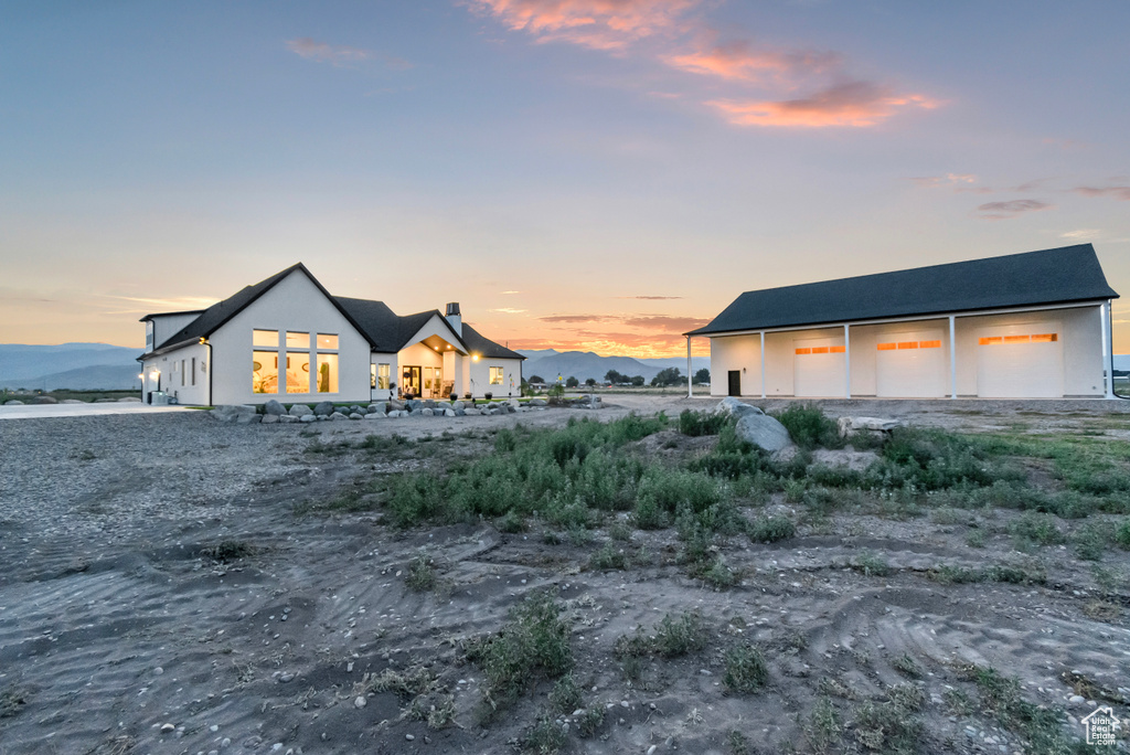 Back of house with a garage, an outbuilding, and stucco siding