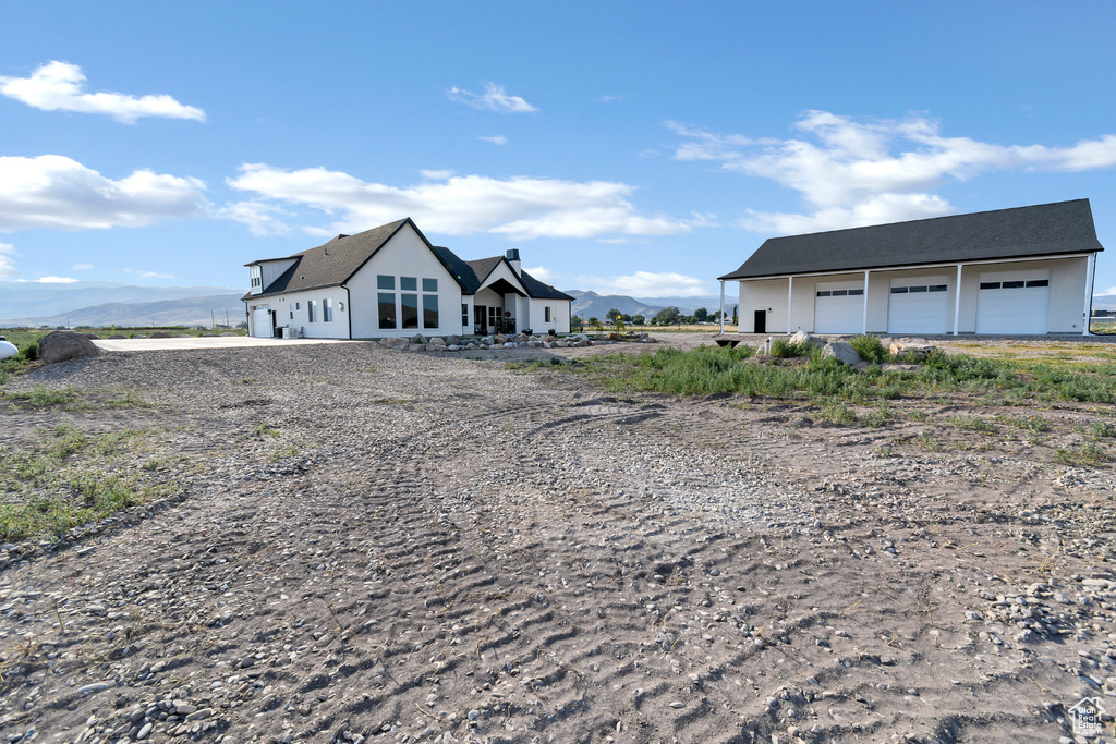 View of front facade with a detached garage, a mountain view, and driveway
