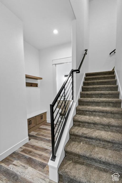 Stairs with wood finished floors and recessed lighting