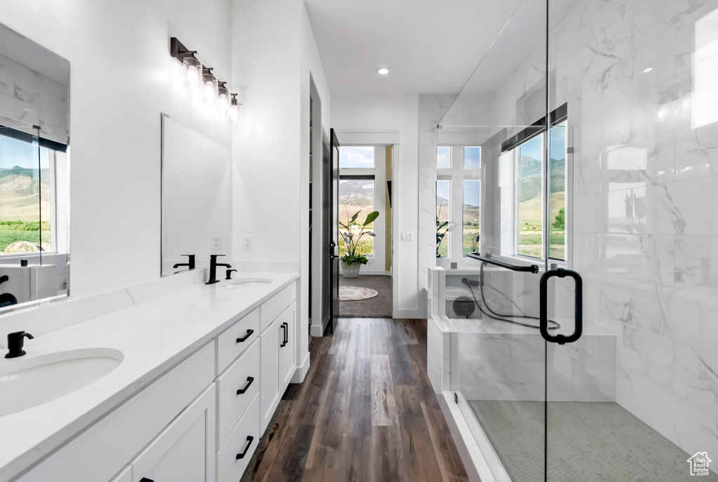 Bathroom featuring healthy amount of natural light, double vanity, a marble finish shower, and recessed lighting