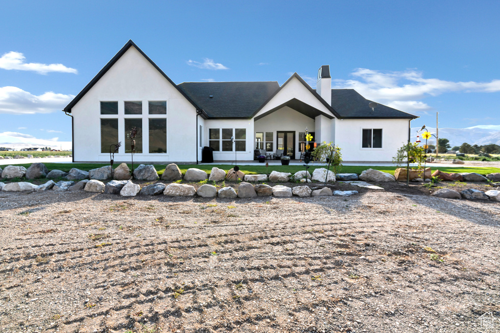Rear view of house with stucco siding and a chimney