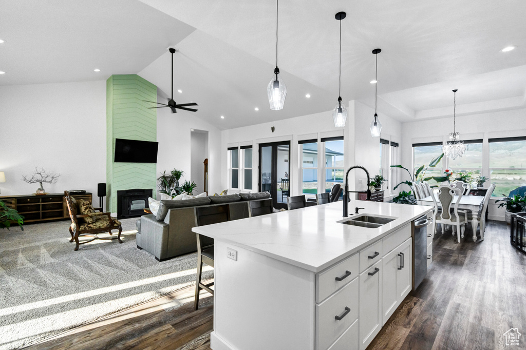 Kitchen with dark wood finished floors, stainless steel dishwasher, a kitchen island with sink, white cabinets, and recessed lighting