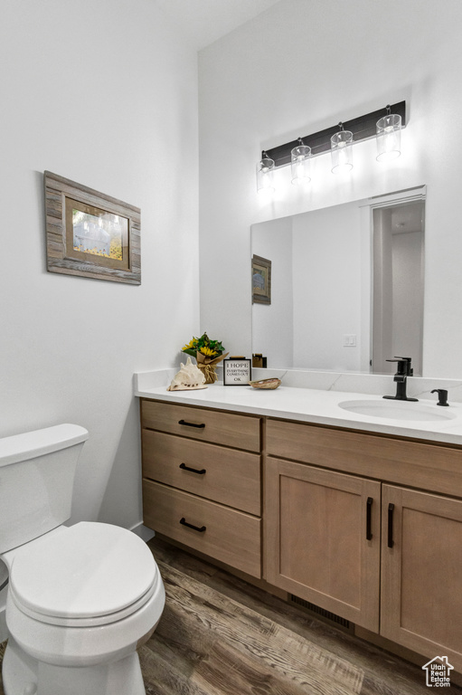 Half bath with vanity and wood finished floors