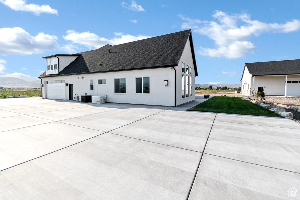 View of front of property featuring concrete driveway, roof with shingles, a front yard, and stucco siding
