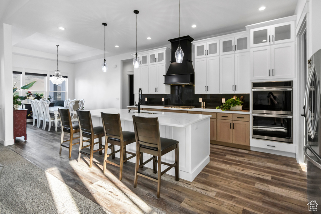 Kitchen featuring appliances with stainless steel finishes, light countertops, decorative backsplash, a chandelier, and dark wood-style floors
