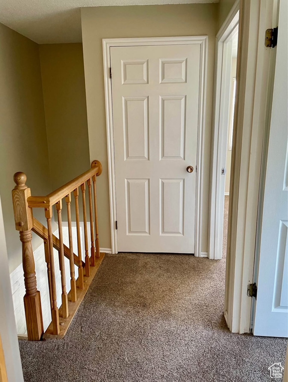 Hall with carpet floors and an upstairs landing